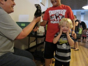 wildlife expert holds up a critter and a little boy has his hands on his face - like oh man.